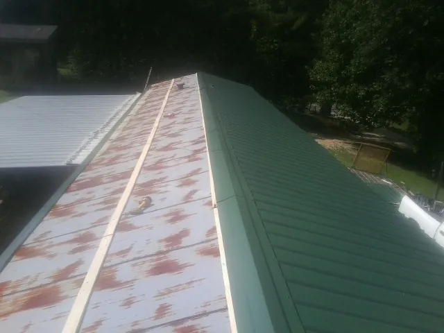 Old rusted panels beside newly installed green metal roofing — Wind Damage Roof Repair by Roofing Brothers in Millersburg
