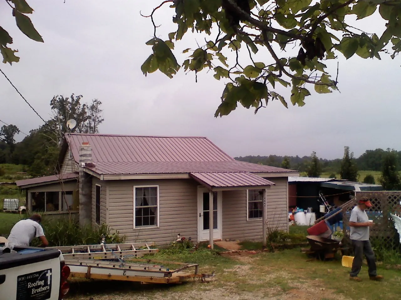 Crew finishing a mauve metal roof on a small farmhouse in Millersburg