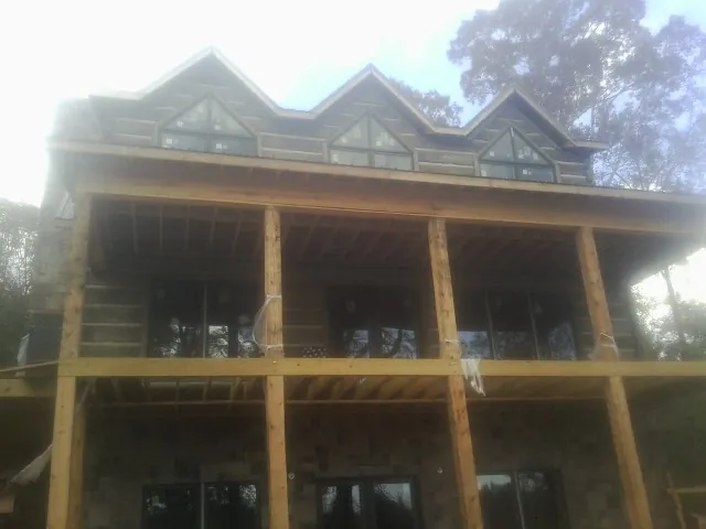 Dormers and porch framing on a large log home under construction — Roof Coating work by our crew in Millersburg