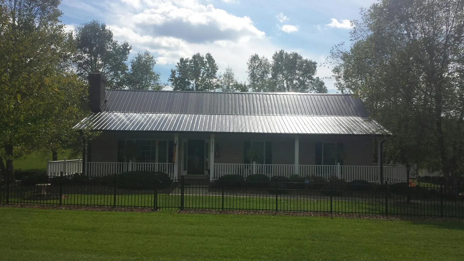 Gray metal roof on a brick ranch with a full width front porch — Gutter Guard Installation work by our crew in Millersburg